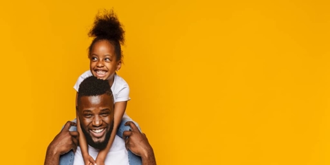 a father holding his daughter on his shoulders